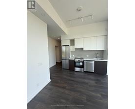 A modern kitchen with dark wood floors and stainless steel appliances.