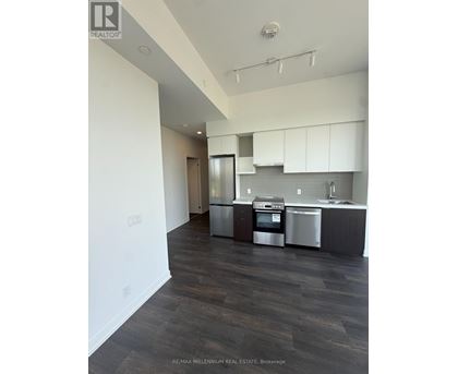 A modern kitchen with dark wood floors and stainless steel appliances.