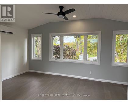 A room with a ceiling fan and three windows.
