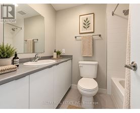 A bathroom with a toilet, sink, and a plant.
