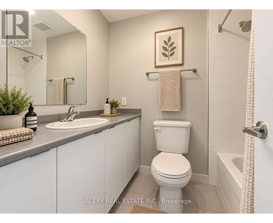 A bathroom with a toilet, sink, and a plant.