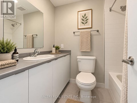 A bathroom with a toilet, sink, and a plant.