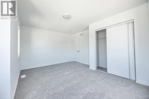 A spacious room with white walls and carpeted floor.