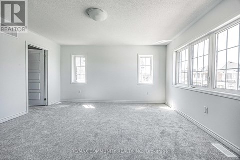 A room with a carpet floor and a door on the left.