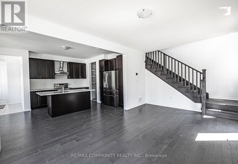 A spacious room with a staircase and a kitchen area.