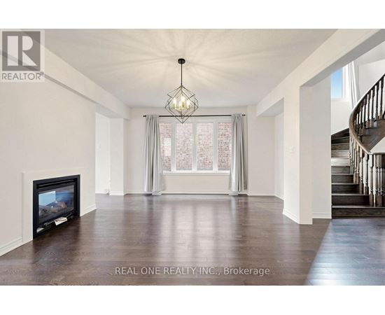 A spacious living room with a fireplace and a staircase.