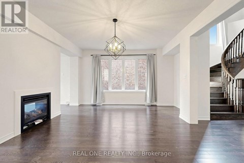 A spacious living room with a fireplace and a staircase.