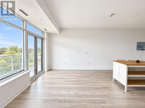 A room with a wooden floor and a white wall with a window and a desk.