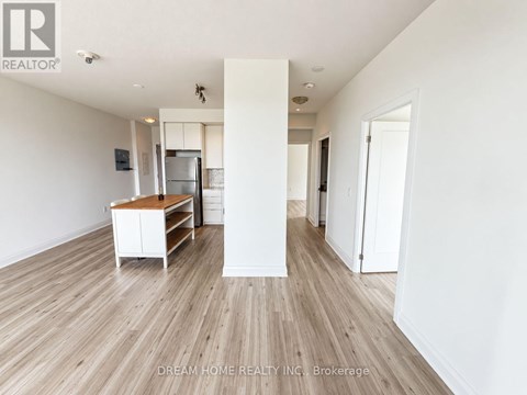 A white room with wood flooring and a white cabinet.