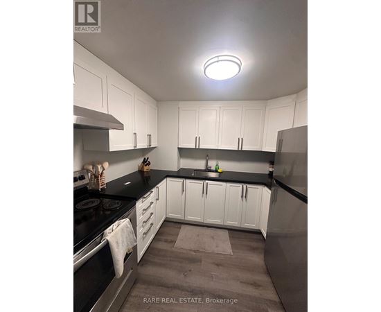 A kitchen with white cabinets and black countertops.