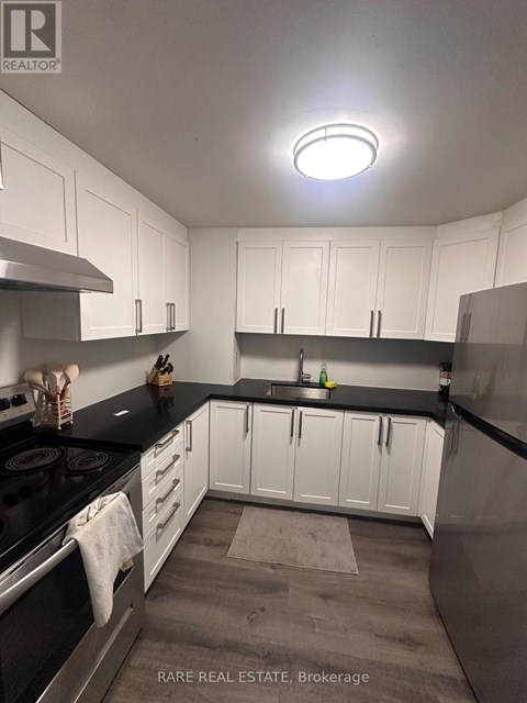 A kitchen with white cabinets and black countertops.