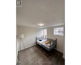 A bedroom with a bed, a floor lamp, and a window.