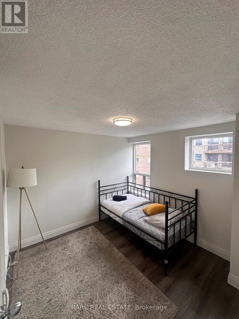 A bedroom with a bed, a floor lamp, and a window.