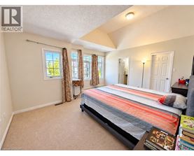A bedroom with a bed, a window with curtains, and a nightstand with a lamp.
