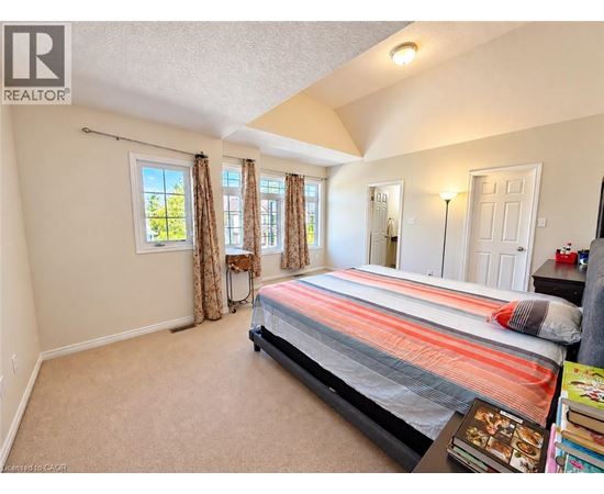A bedroom with a bed, a window with curtains, and a nightstand with a lamp.