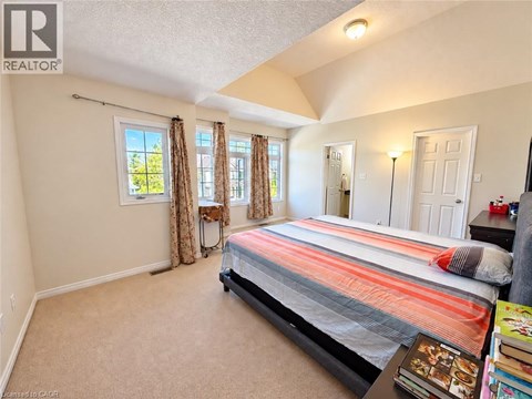 A bedroom with a bed, a window with curtains, and a nightstand with a lamp.