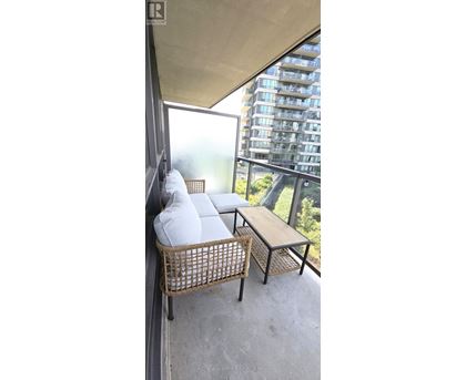 A balcony with a wicker chair and a small table.