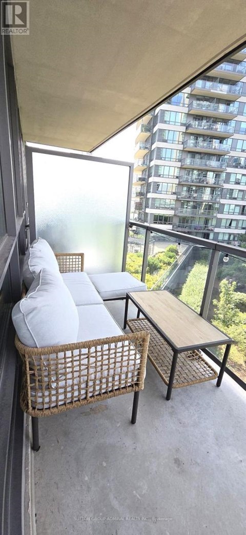 A balcony with a wicker chair and a small table.