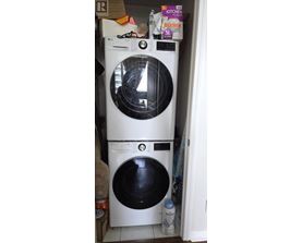 A white washing machine with a black door is in a cluttered kitchen.