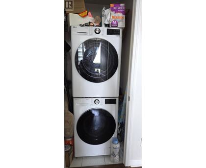 A white washing machine with a black door is in a cluttered kitchen.