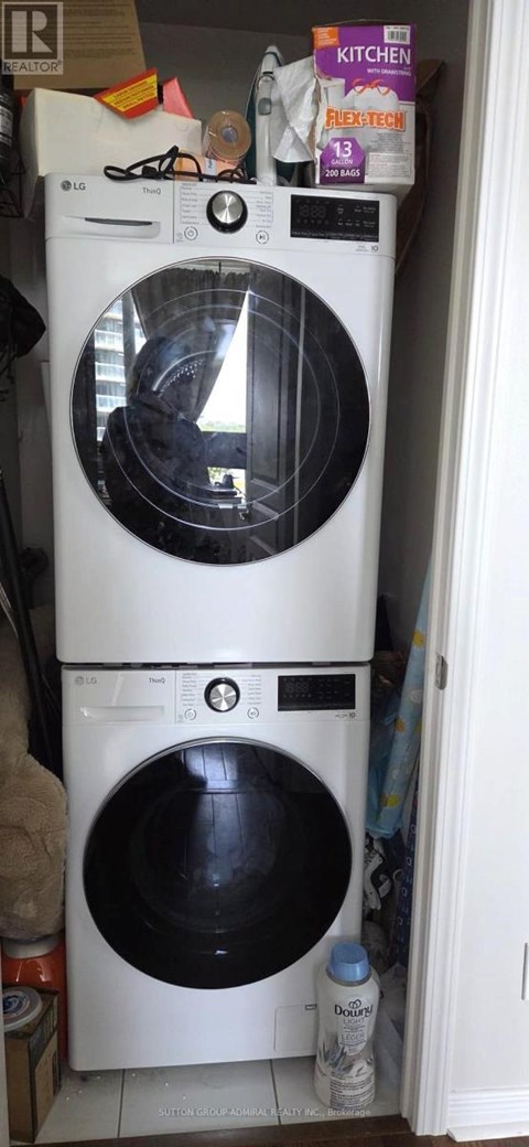 A white washing machine with a black door is in a cluttered kitchen.