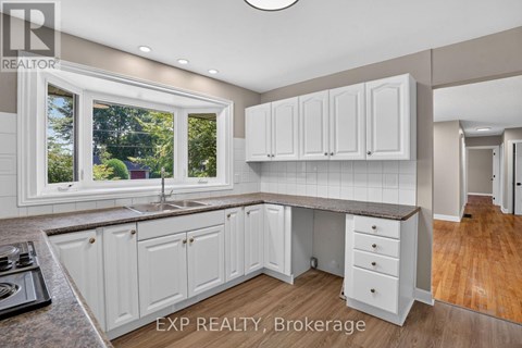 A kitchen with white cabinets and a window overlooking a tree.
