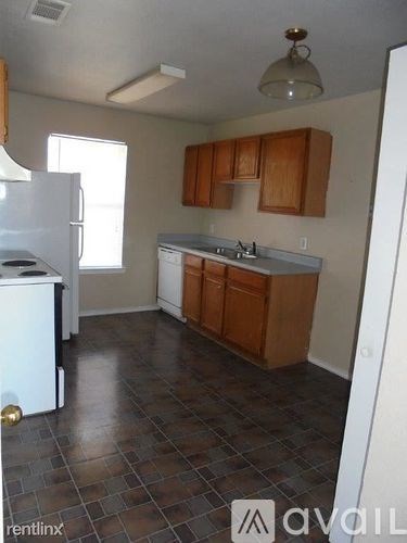 A kitchen with a white fridge and wooden cabinets.