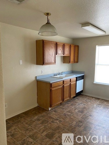 A kitchen with wooden cabinets and a tiled floor.