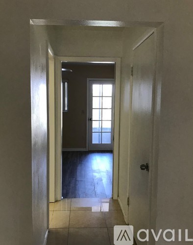 A hallway with a door on the right and a window on the left.