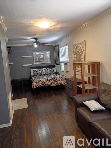 A living room with a brown leather couch and a grey wall.