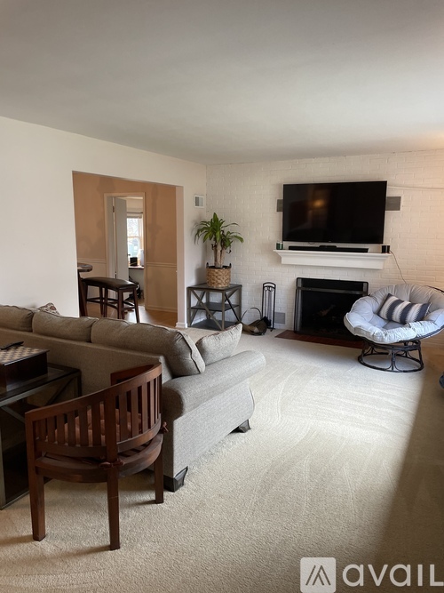 A living room with a grey couch, a wooden chair, a television, and a fireplace.