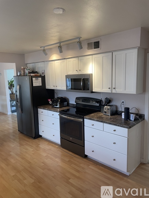 A kitchen with white cabinets and a black fridge.
