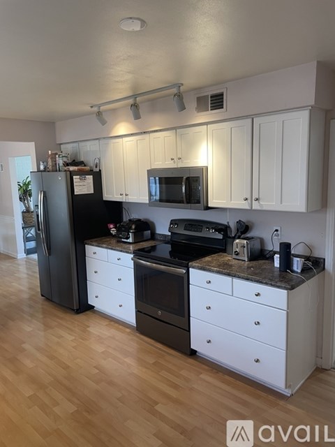 A kitchen with white cabinets and a black fridge.