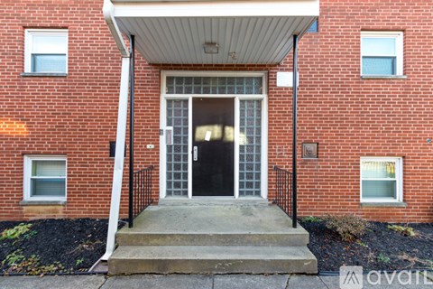 A red brick building with a black gate and a white awning.