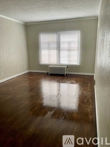 A room with a wooden floor and a window with blinds.