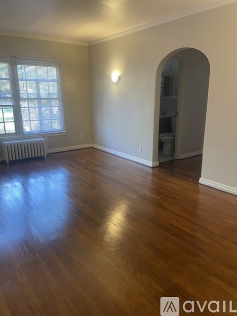 A room with wooden floors and a window with blinds.