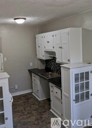 A kitchen with white cabinets and a black countertop.