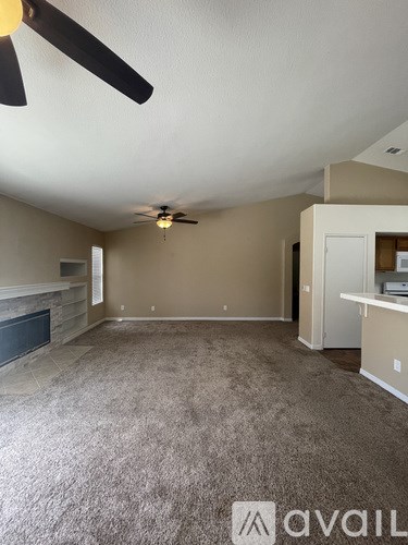 A spacious room with a ceiling fan and a fireplace.