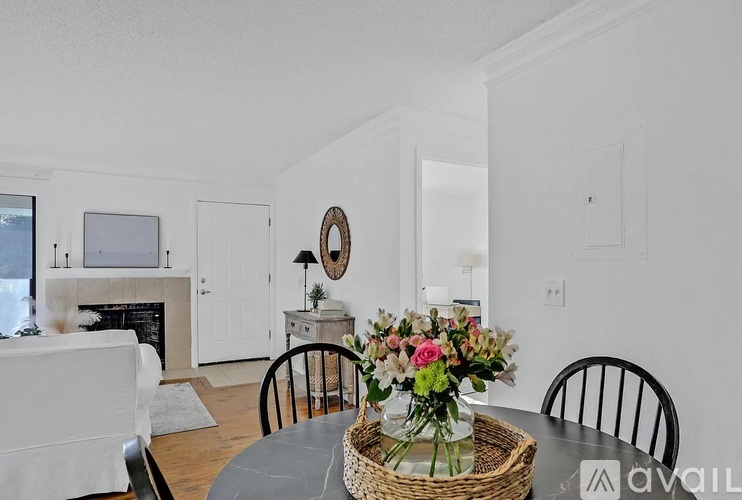 A dining room with a table set for two and a basket of flowers on the table.