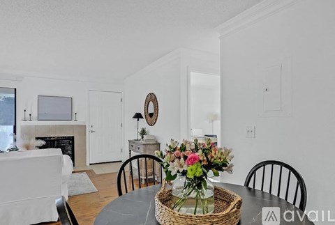 A dining room with a table set for two and a basket of flowers on the table.