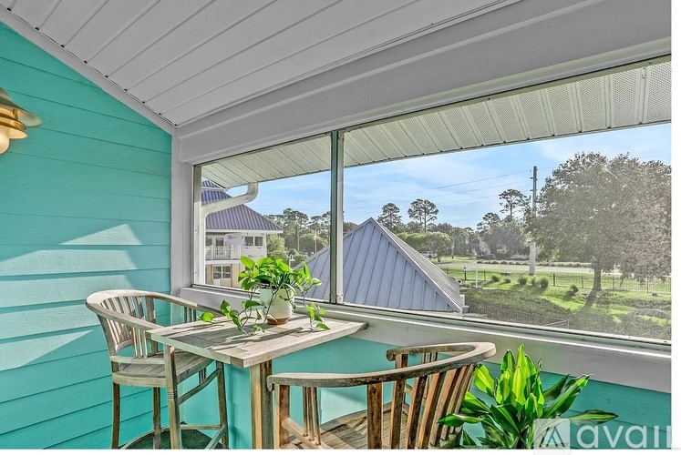 A table with chairs is set up on a balcony with a view of a house and trees.