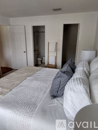 A bedroom with a bed in the foreground and a toilet visible in the background.