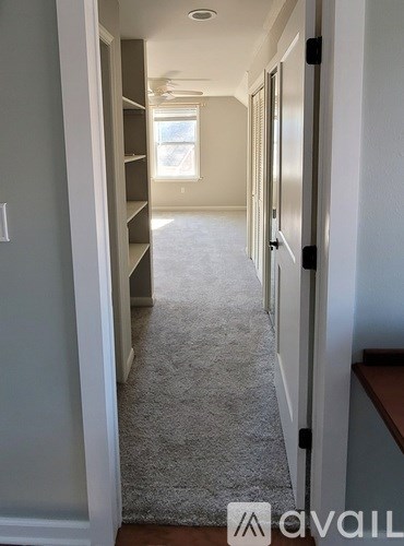 A hallway with a carpeted floor and a window.