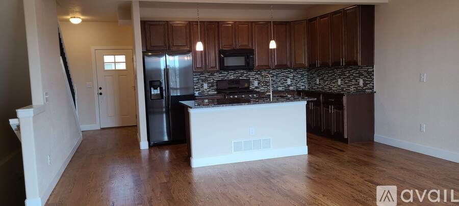 A kitchen with wooden cabinets and a black fridge.