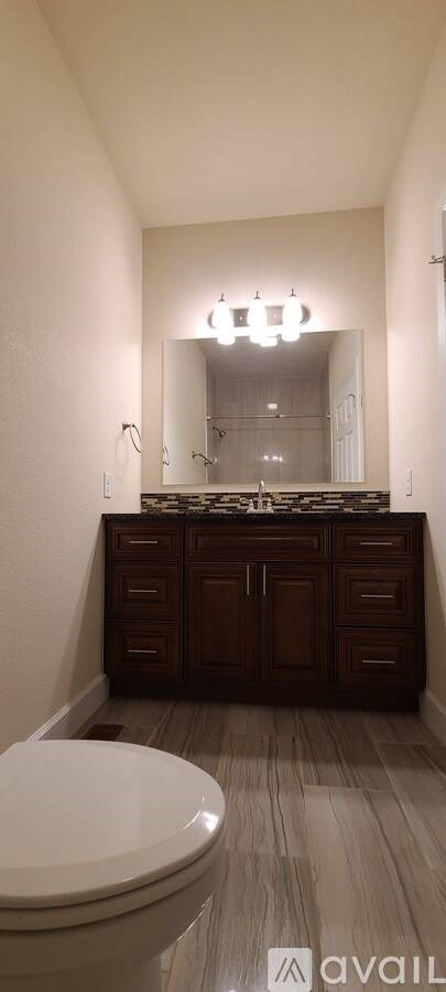 A bathroom with a toilet and a vanity with a mirror above it.