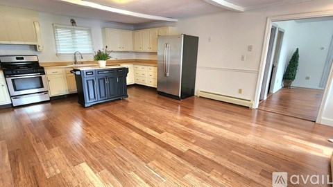 A kitchen with wooden floors and a black refrigerator.