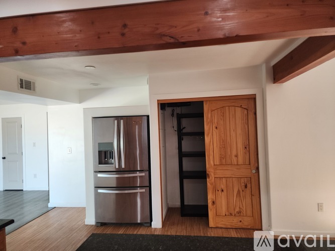 A kitchen with a stainless steel refrigerator and a wooden door.
