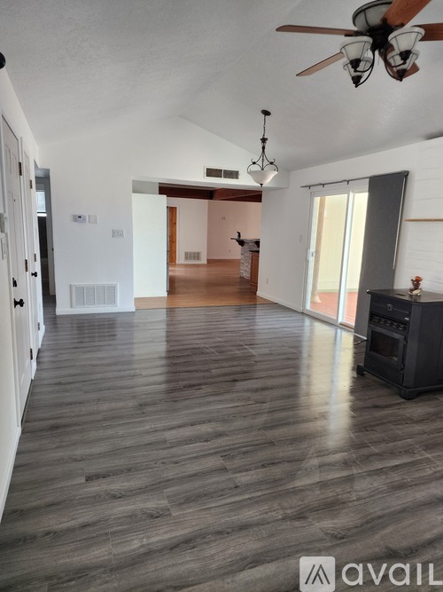 A spacious room with a ceiling fan and wooden flooring.