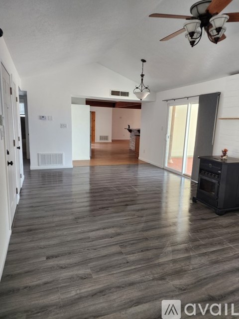 A spacious room with a ceiling fan and wooden flooring.