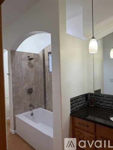 A bathroom with a white bathtub and a black countertop.